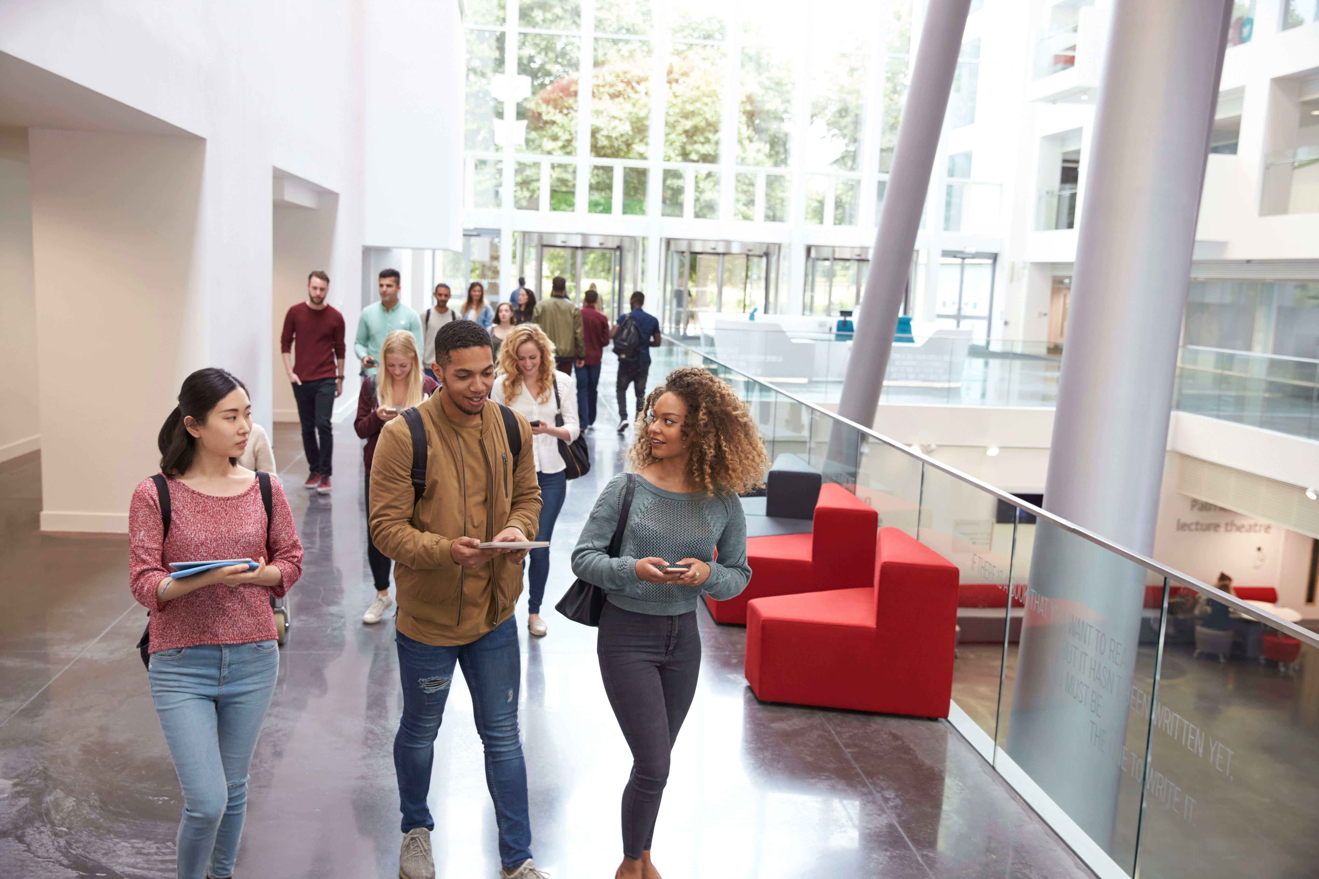 A diverse group of students walk through a hallway on a college campus