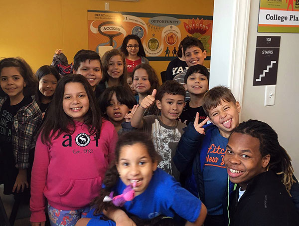 Framingham State University sophomore Deron Hines (lower right) welcomes 
Woodrow Wilson Elementary School students to the College Planning Center’s “College for a Day” program.